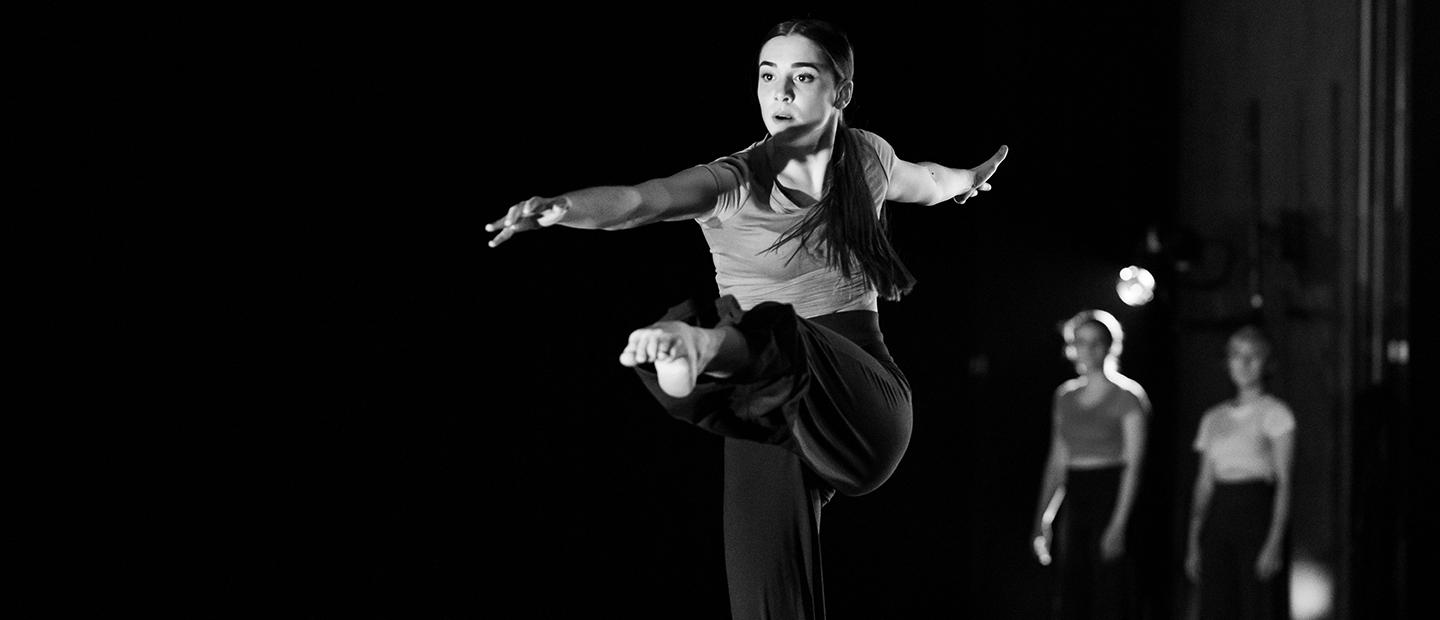舞台上一个独舞的女舞者伸展着腿的形象