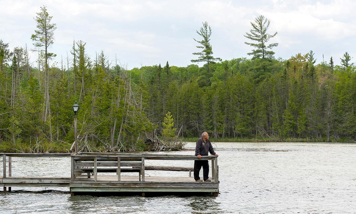 Man standing at edge of dock looking over lake