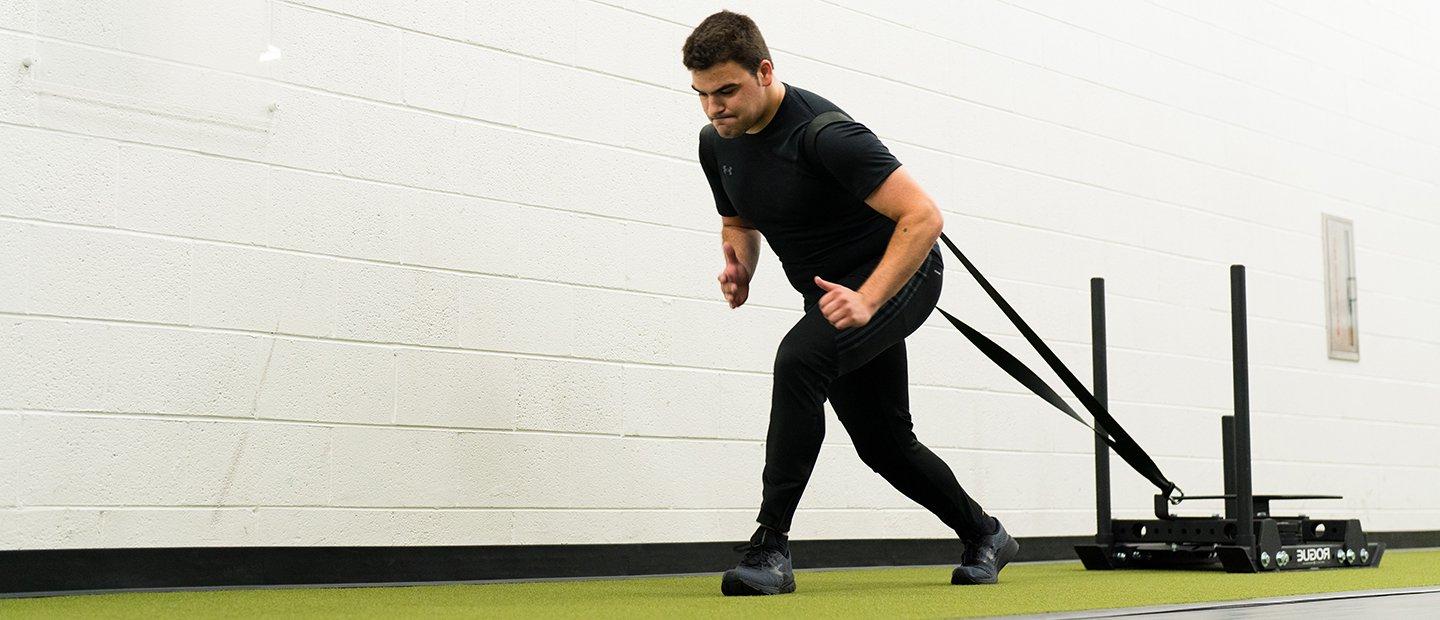 A man pulling a weight sled in the recreation center.