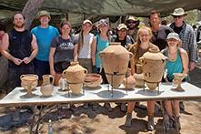 Students and faculty group standing in front of archaeological artifacts