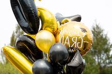 图片上有大小不一的黑色和金色气球，其中有祝贺毕业的文字! on it