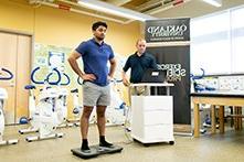 在健身科学教室里，一名男子带着健身器材站在电子设备上.
