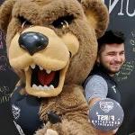 埃内斯托Duran-Gutierrez, 拿着第一代365英国上市官网的按钮, 与棕熊吉祥物合影.